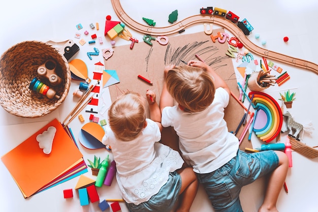 Crianças desenham e fazem artesanato. Crianças com brinquedos educativos e material escolar para a criatividade. Plano de fundo para pré-escola e jardim de infância ou aulas de arte. Menino e menina brincando em casa ou na creche