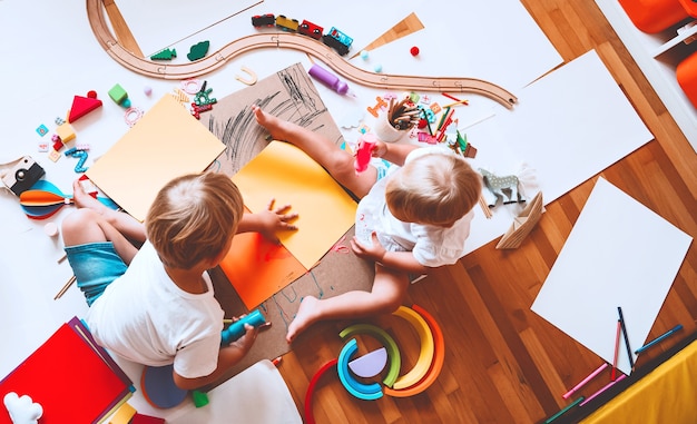 crianças desenham e fazem artesanato infantil com brinquedos educativos na pré-escola e jardim de infância ou aulas de arte