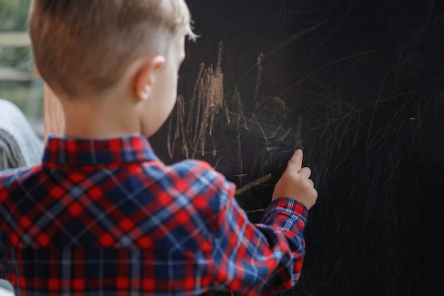 Foto crianças desenham. menino escreve em um quadro negro.