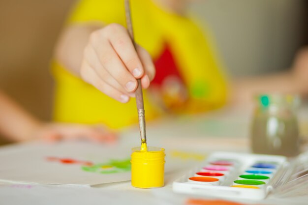 Crianças desenhando com tintas coloridas nos papéis.