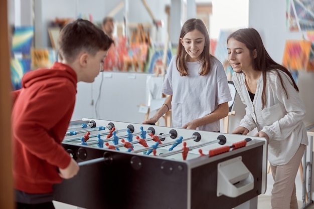 Foto crianças do ensino fundamental em uma sala de aula jogando futebol de mesa. diversão durante o recreio na escola.