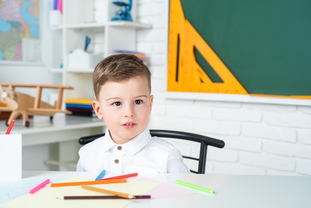 Crianças do ensino fundamental na escola Criança bonita está sentada em uma mesa dentro de casa