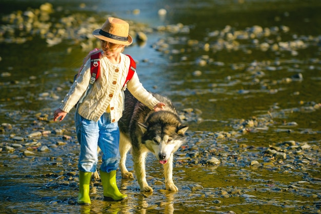 Crianças e cachorro explorando Crianças bonitas com cachorro andando no rio em um dia ensolarado de verão Crianças turistas e cachorro na bela natureza