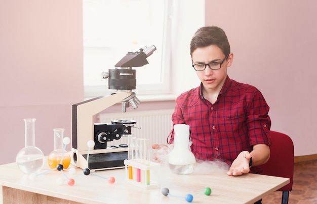 Crianças e ciência. Adolescente confuso conduzindo experimentos com nitrogênio líquido em laboratório com reagentes, tubos de ensaio e frascos. Desenvolvimento inicial, inovação, educação integrada