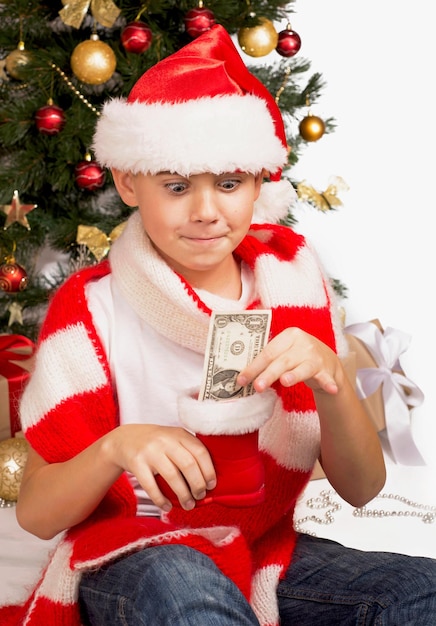 Crianças e dinheiro O menino recebeu uma nota de um dólar no Natal Crianças de Natal Crianças felizes Abrindo presentes de ano novo Menino recebendo presentes de Natal