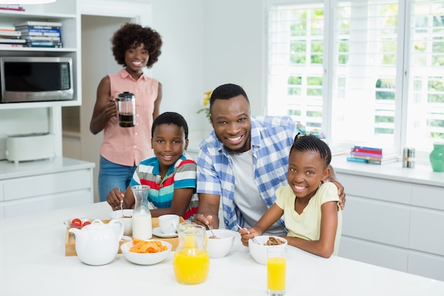 Crianças e pais tomando café da manhã na mesa em casa