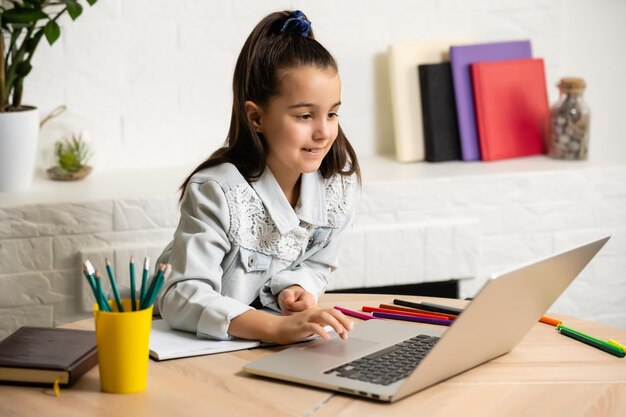 crianças, educação e conceito de aprendizagem à distância - menina estudante com computador portátil em casa