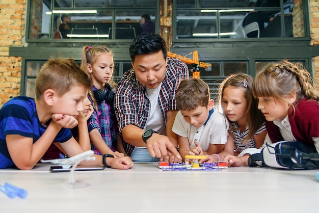 Crianças em idade escolar criativas com jovem professor asiático estudam um construtor eletrônico com ventilador e ligue flashlight.school.