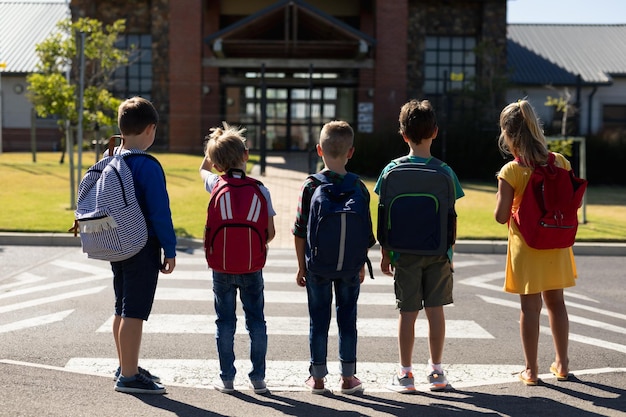 Crianças em idade escolar esperando em uma passagem para pedestres para atravessar a rua