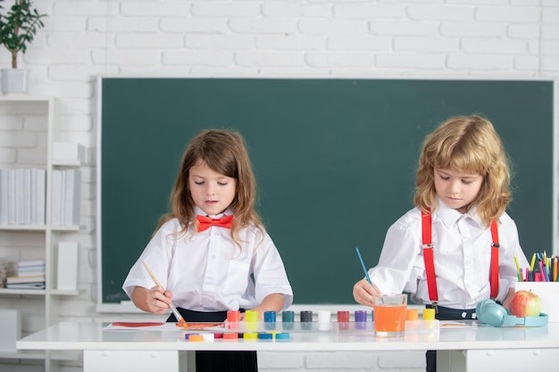 Crianças em idade escolar menina e menino pintando com tintas cor e pincel em sala de aula Crianças arte criatividade crianças conceito