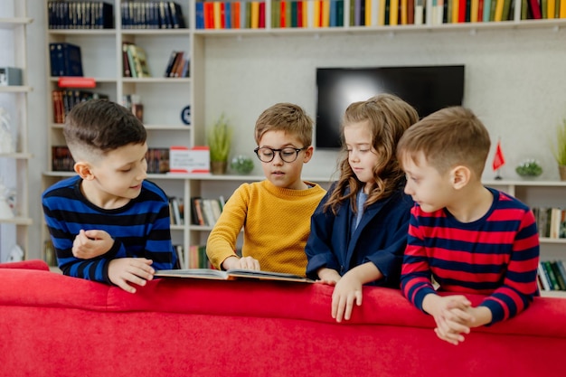 Crianças em idade escolar na biblioteca lendo livros, fazendo lição de casa, preparam um projeto escolar para aulas