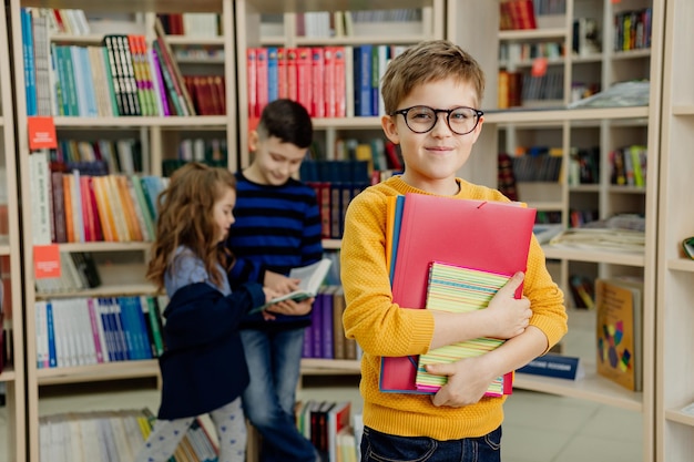 Crianças em idade escolar na biblioteca lendo livros, fazendo lição de casa, preparando-se para as aulas