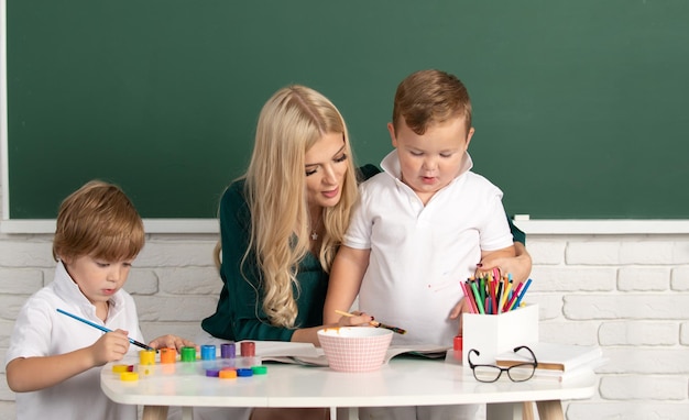 Crianças em sala de aula do ensino fundamental desenhando na mãe professora de jardim de infância trabalhando com crianças criativas