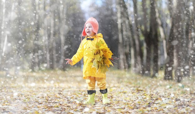Crianças em uma caminhada no parque outono. Primeira geada e a primeira neve na floresta de outono. As crianças brincam no parque com neve e folhas.