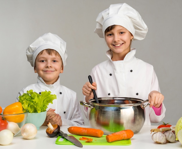 Crianças em uma mesa com legumes