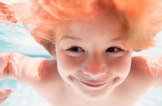 Crianças engraçadas com rostos debaixo d'água Criança debaixo d'água na piscina Criança bonita a nadar na piscina