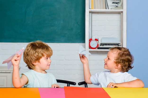 Crianças engraçadas da escola primária seguram avião de papel rindo e sorrindo crianças educação engraçada ...