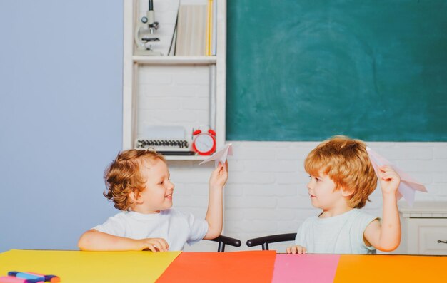 Crianças engraçadas da escola primária seguram avião de papel rindo e sorrindo crianças engraçadas educação pré