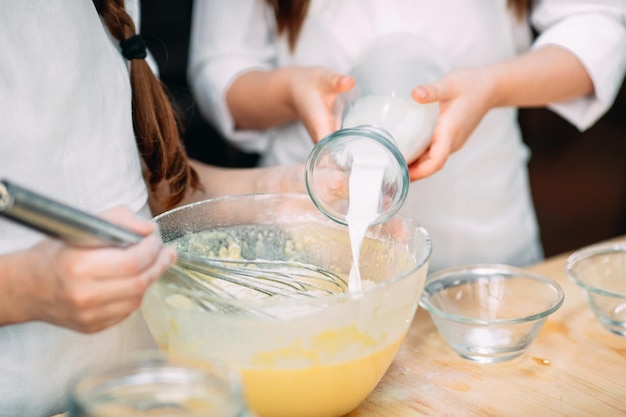 Crianças engraçadas estão preparando a massa na cozinha.