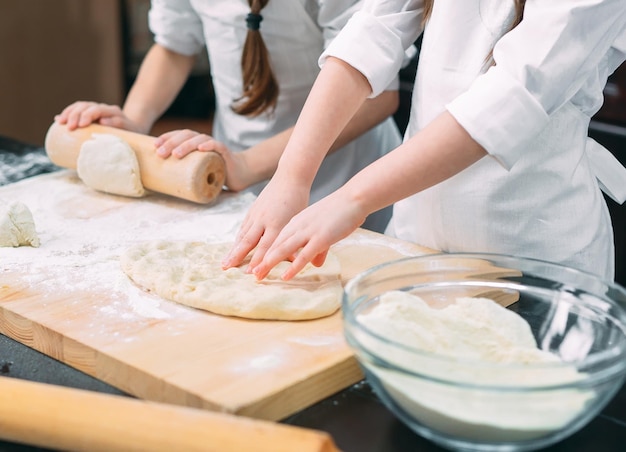 Crianças engraçadas estão preparando a massa na cozinha.