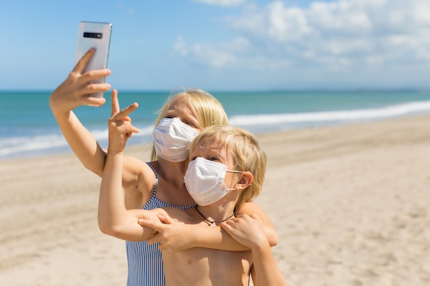 Foto crianças engraçadas tirando foto de selfie por smartphone na praia do mar tropical.