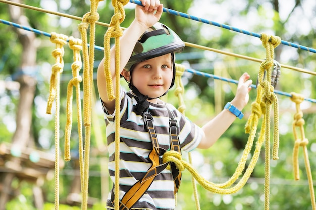 Crianças escalando no parque de aventura. O menino gosta de escalar na aventura do curso de cordas. Criança escalando parque de arame alto