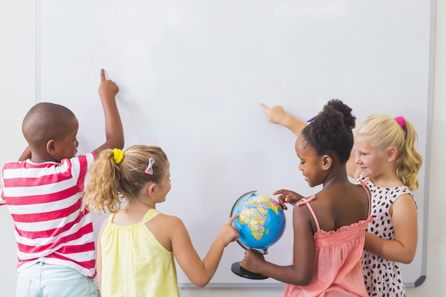 Crianças estudando o globo na sala de aula