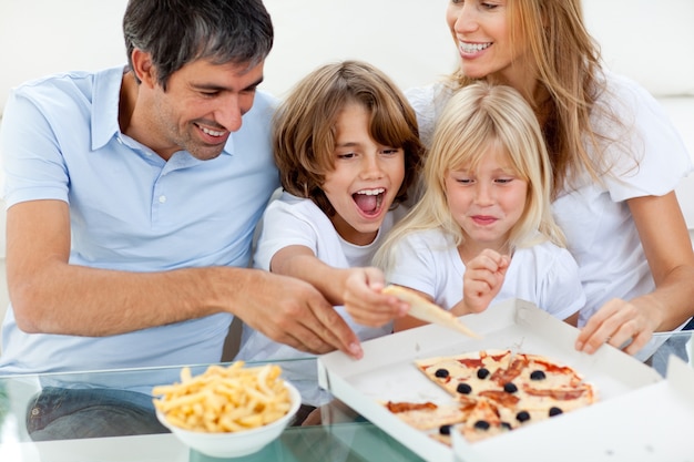 Crianças excitadas comendo uma pizza com seus pais