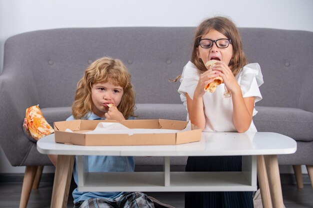 Crianças famintas comendo pizza crianças engraçadas e fofas menina e menino comendo pizza saborosa