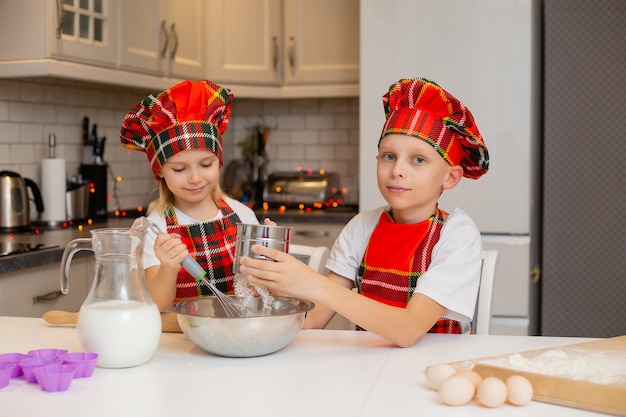 Crianças fantasiadas de chef preparam massa com farinha, leite, ovos e manteiga para os doces de Natal