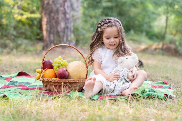 Crianças fazem piquenique menina bonitinha abraça ursinho e desfrutando de piquenique no parque