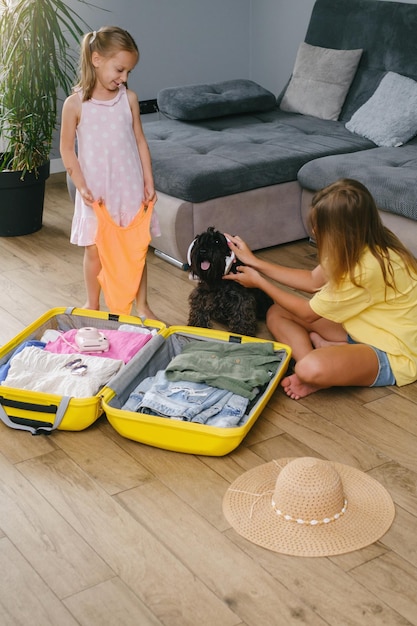 Crianças fazendo as malas para viajar e brincando com um cachorro em fones de ouvido