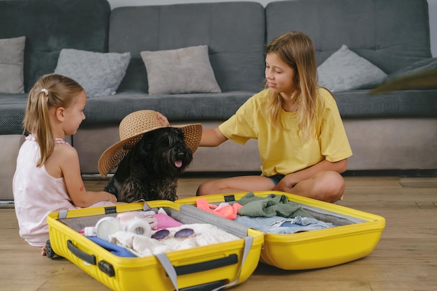 Crianças fazendo as malas para viajar e brincando com um cachorro em fones de ouvido