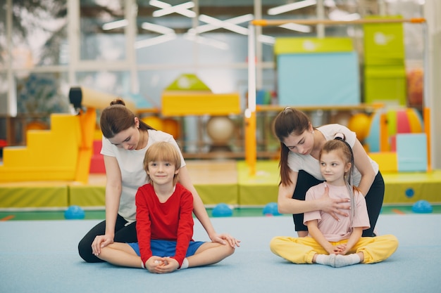 Crianças fazendo exercícios de alongamento na academia, no jardim de infância ou no ensino fundamental, esporte e conceito de fitness