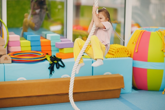 Crianças fazendo exercícios de escalada na corda bamba no ginásio, no jardim de infância ou na escola primária. Conceito de esporte e fitness de crianças.