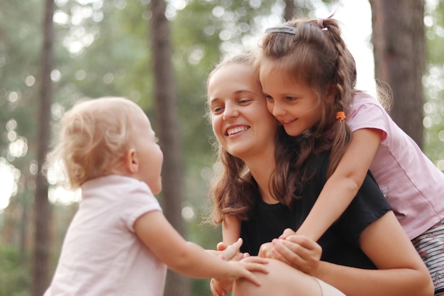 Crianças felicitando a mamãe com o dia das mães Família caucasiana feliz brincando em um parque ensolarado Mulher abraçando com suas filhas sorrindo feliz desfrutando de momentos agradáveis em família durante o verão caminhar ao ar livre