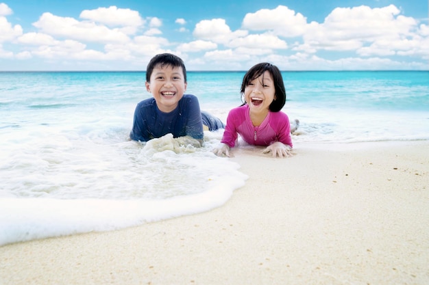 Crianças felizes a brincar de ondas na praia.