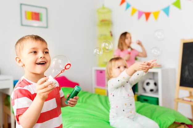 Foto crianças felizes a soprar bolhas de sabão em casa.