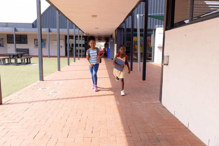 Foto crianças felizes afro-americanas correndo com cadernos na escola.