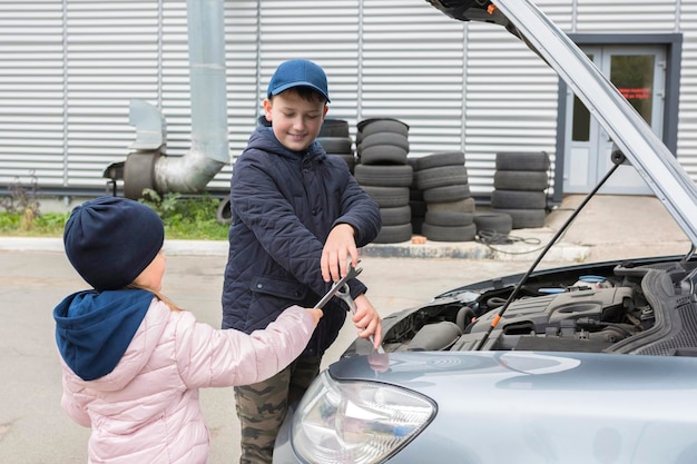 Crianças felizes ao ar livre estão consertando um serviço de reparo de automóveis