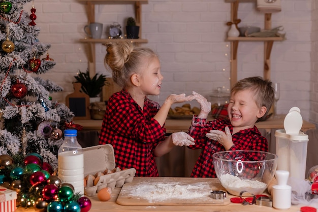 Crianças felizes assam biscoitos de Natal em casa na cozinha