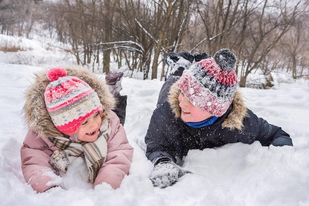 Crianças felizes brincam em um monte de neve no inverno Férias e feriados de inverno