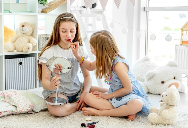 Crianças felizes brincando com batom de maquiagem