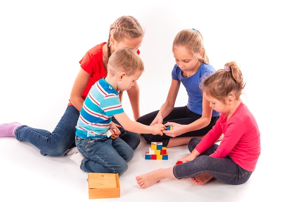 Crianças felizes brincando com blocos de construção isolados no branco. Trabalho em equipe, conceito de criatividade.