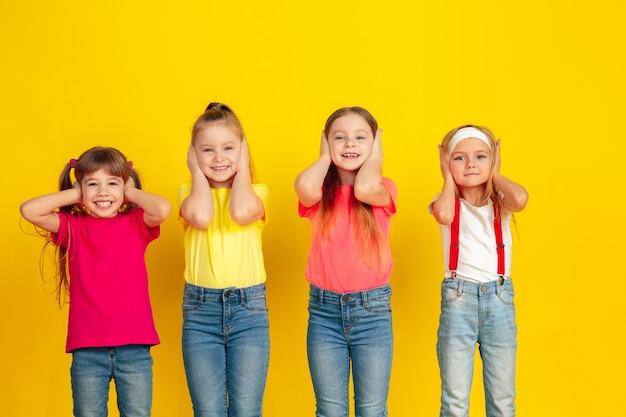 Crianças felizes brincando e se divertindo juntas na parede amarela