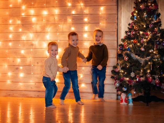 Foto crianças felizes brincando perto da árvore de natal