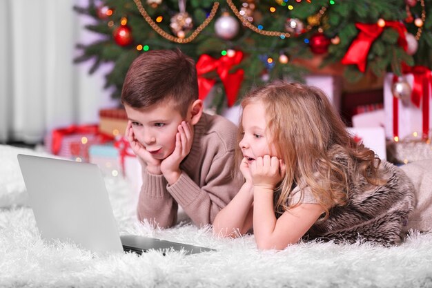 Crianças felizes com laptop na sala decorada de Natal