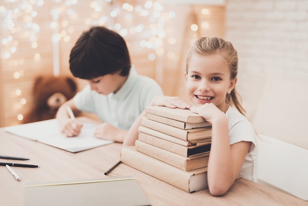 Crianças felizes com livros empilhados na mesa