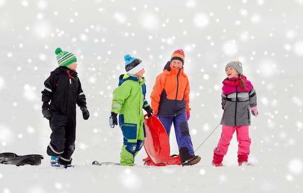 Crianças felizes com trenós a andar de trenó no inverno.