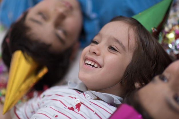 Crianças felizes comemorando festa com confete soprando enquanto estava deitado no chão